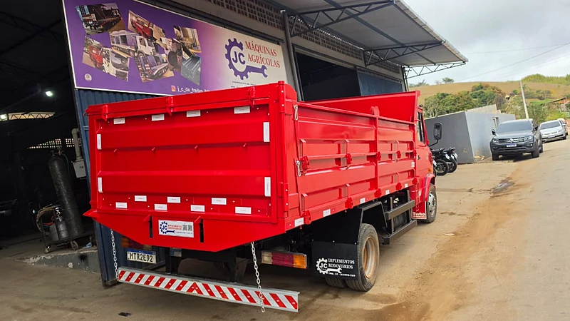Caminhão com caçamba vermelha pronta, em frente à fachada da JC