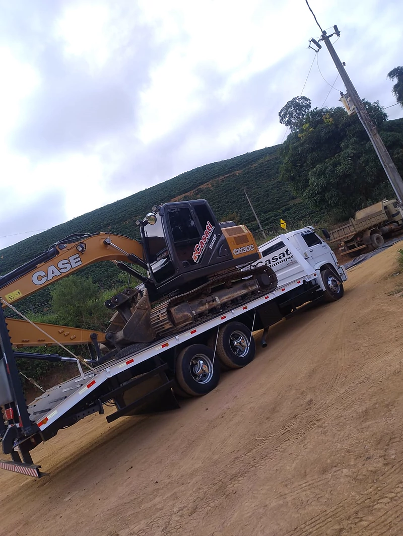 Escavadeira sendo transportada sobre plataforma da JC, em campo